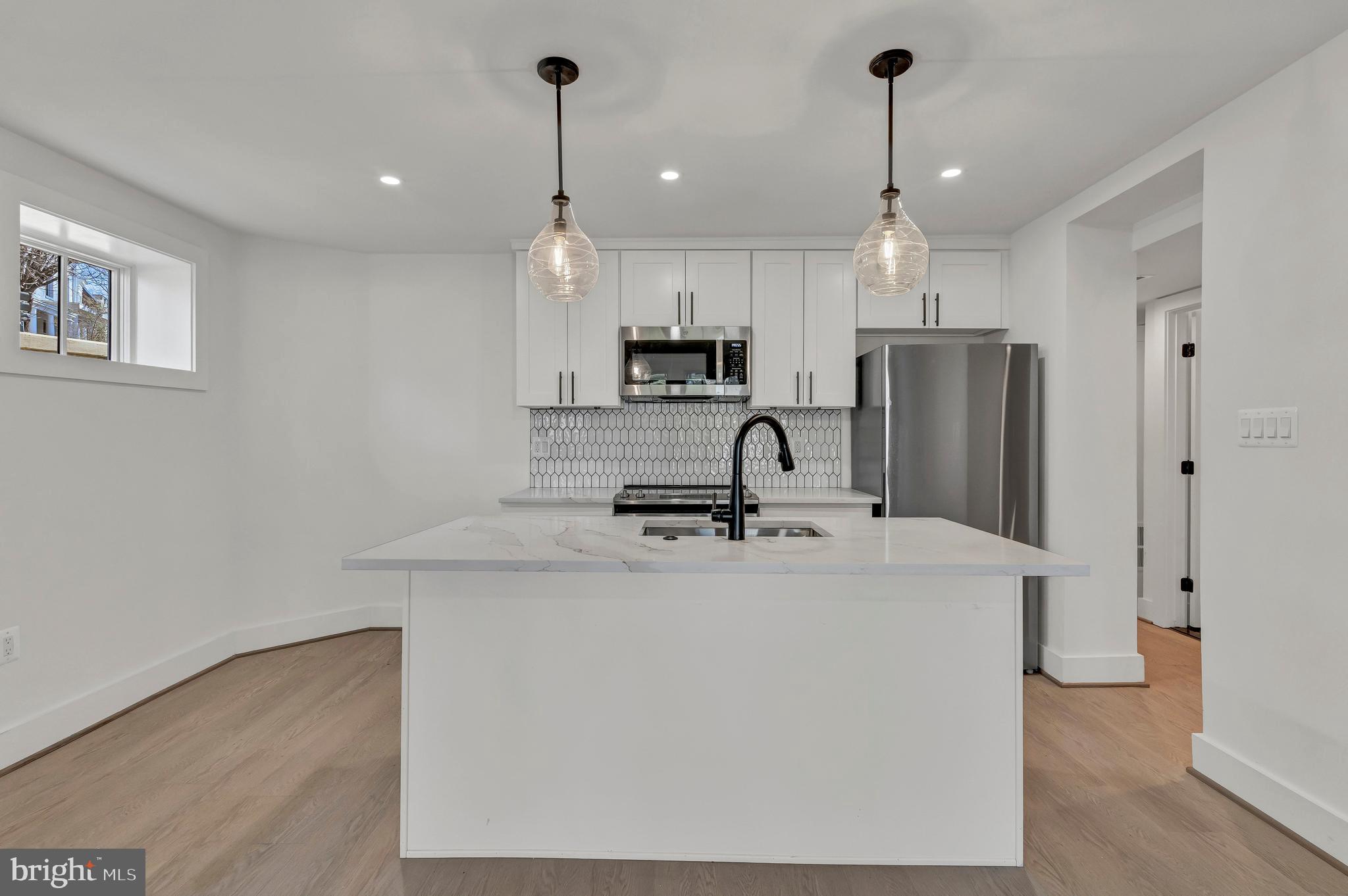 2001 Klingle Road Northwest Washington, DC 20010 - Photo 46 of 50 a kitchen with stainless steel appliances granite countertop a refrigerator a sink a stove a microwave and white cabinets