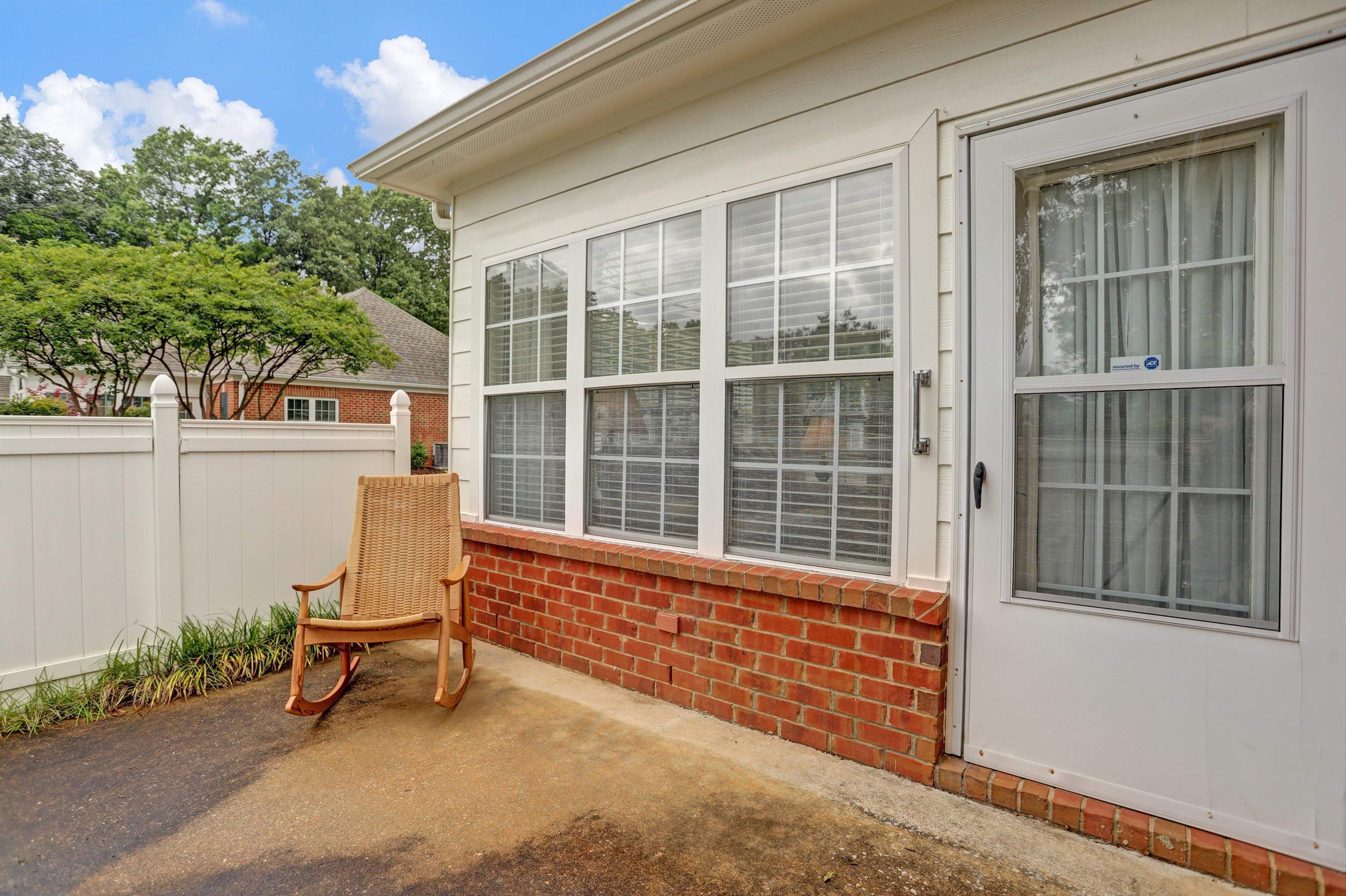 34 Peyton Ridge Drive, Unit 21 Collierville, TN 38017 - Photo 6 of 37 Exterior patio area featuring a white vinyl privacy fence, red brick foundation, and multi-pane windows with blinds