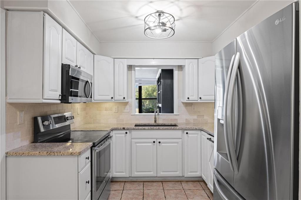 34 Chaumont Square Northwest Atlanta, GA 30327 - Photo 15 of 42 a kitchen with stainless steel appliances granite countertop a sink a stove a refrigerator a microwave oven with cabinets and wooden floor