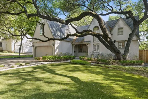 a view of a house with a yard and large tree