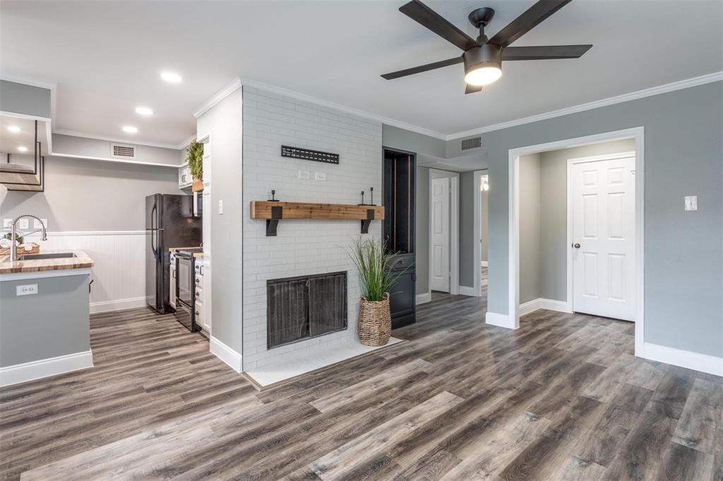 16301 Ledgemont Lane, Unit 283 Addison, TX 75001 - Photo 5 of 16 Stunning living space with wood fireplace, decorative mantle, ceiling fan and open concept to kitchen and dining areas.