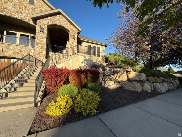 4536 North 475 East Provo, UT 84604 - Photo 60 of 65 Stone facade exterior featuring a covered entry, wrought iron railings, tiered landscaping, and a natural stone retaining wall