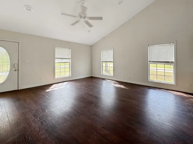 a view of an empty room with wooden floor and window
