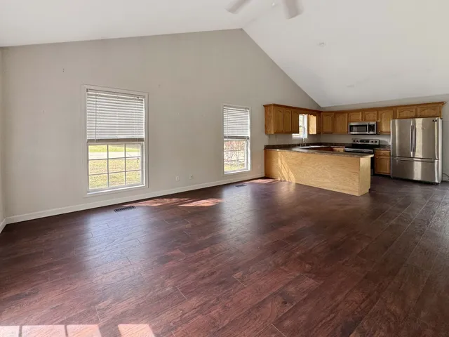 a living room with stainless steel appliances kitchen island hardwood floor and a window