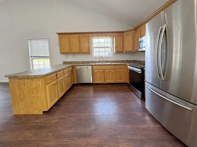 a kitchen with granite countertop a refrigerator and a stove top oven