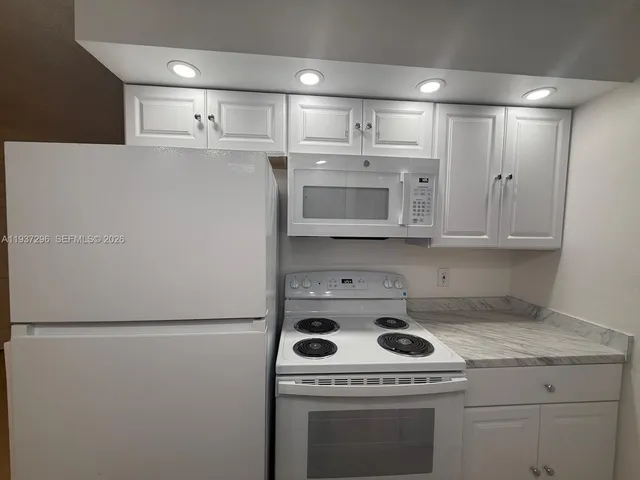 a view of a kitchen with a stove wooden floor and cabinets