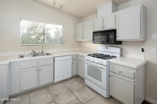 a kitchen with cabinets appliances a sink and a window