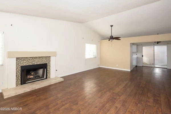 a view of an empty room with wooden floor fireplace and a window