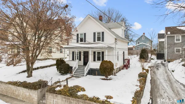 a view of a white house with a yard covered in snow