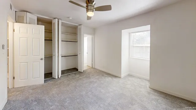 an empty room with closet and windows