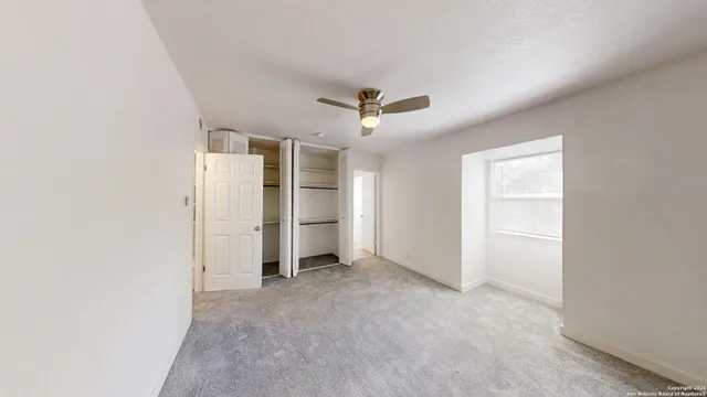 an empty room with closet and a ceiling fan