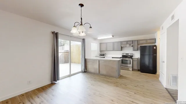 a large kitchen with stainless steel appliances granite countertop a refrigerator a sink dishwasher a stove and white countertops with wooden floor