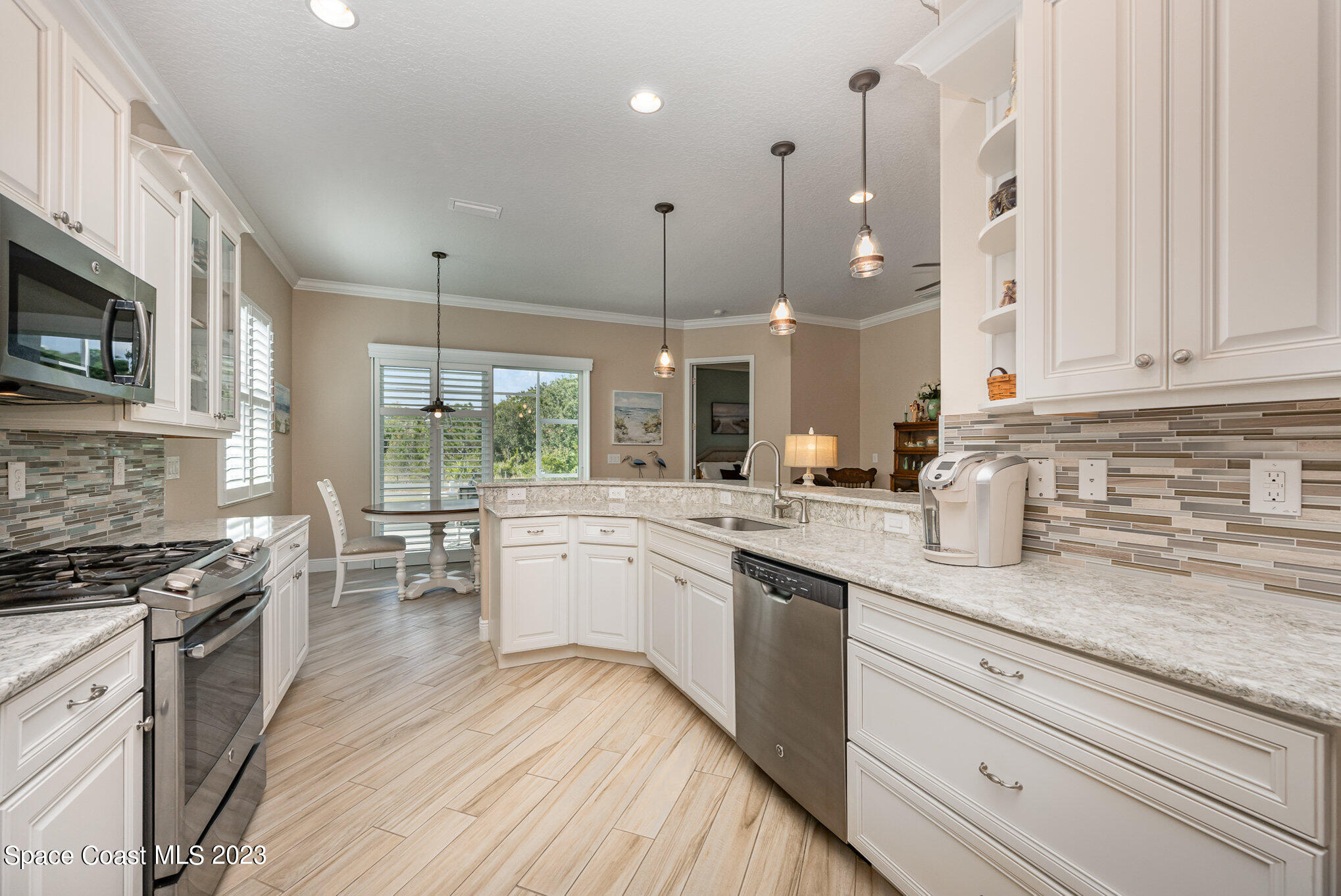3850 Alamanda Key Drive Melbourne, FL 32901 - Photo 6 of 44 a kitchen with stainless steel appliances granite countertop a stove a sink and white cabinets with wooden floor