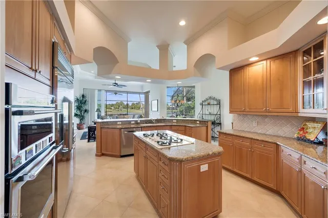 a kitchen with stainless steel appliances granite countertop a stove a sink dishwasher and a refrigerator with wooden floor