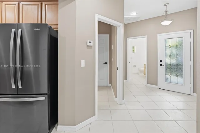 a view of a refrigerator in kitchen and an empty room
