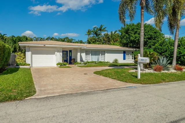 a front view of a house with a yard and palm trees