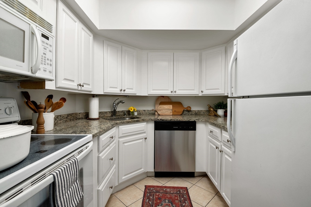 135 Pleasant Street, Unit 403 Brookline, MA 02446 - Photo 6 of 18 a kitchen with stainless steel appliances granite countertop a refrigerator sink and cabinets