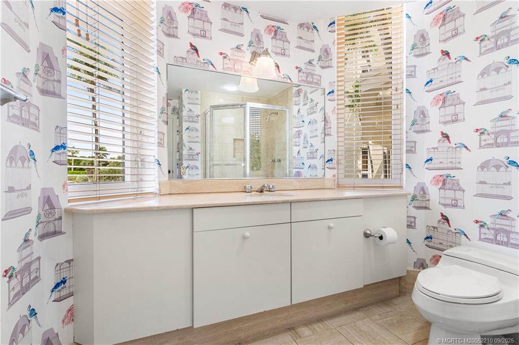 3001 Southeast Island Point Lane, Unit 14 Stuart, FL 34996 - Photo 12 of 38 a bathroom with a sink a toilet a mirror and shower curtain