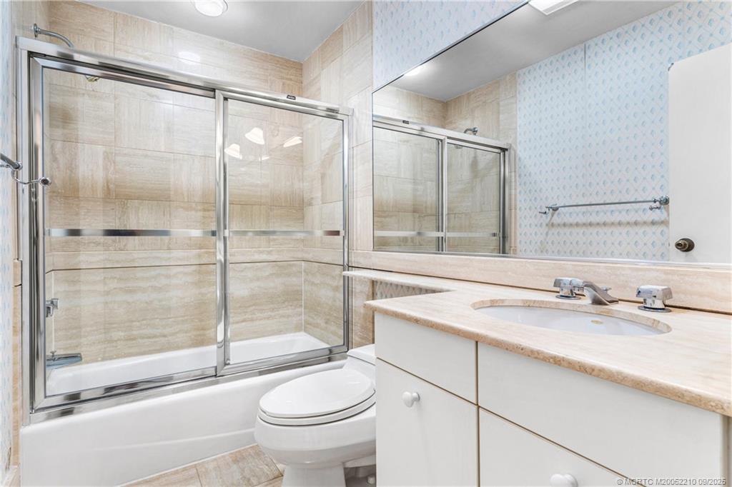 3001 Southeast Island Point Lane, Unit 14 Stuart, FL 34996 - Photo 14 of 38 a bathroom with a shower sink vanity mirror and toilet