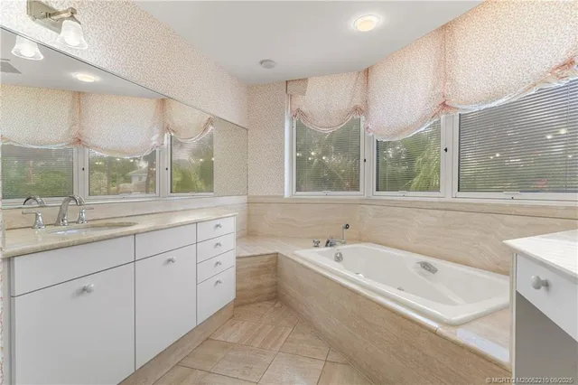 a spacious bathroom with a double vanity sink a mirror and a bathtub next to a window