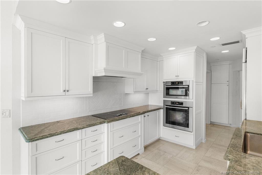 3001 Southeast Island Point Lane, Unit 14 Stuart, FL 34996 - Photo 7 of 38 a kitchen with granite countertop white cabinets and stainless steel appliances