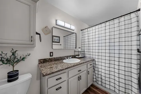 a bathroom with a granite countertop sink a toilet and a mirror