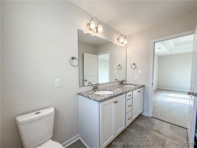 a bathroom with a granite countertop toilet a sink and a mirror