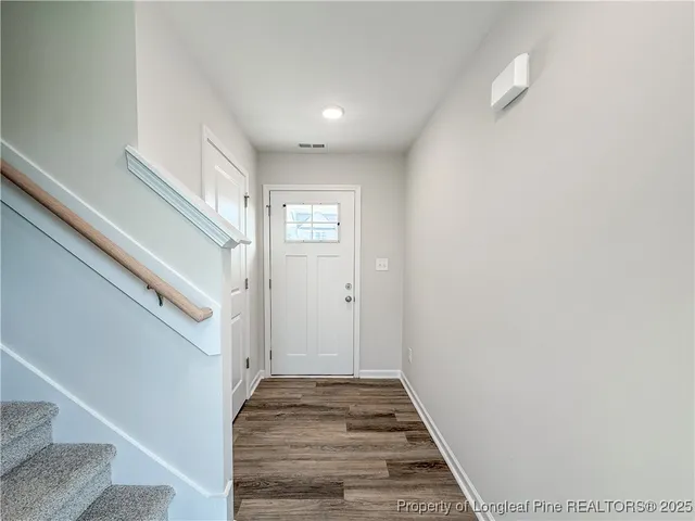 a view of a hallway with white walls and a window