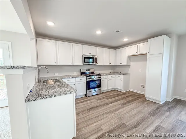 a kitchen with granite countertop a refrigerator stove top oven and sink