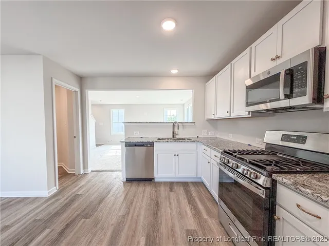 a kitchen with granite countertop wooden cabinets stainless steel appliances and a window
