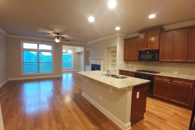 a kitchen with stainless steel appliances granite countertop a sink a stove and a wooden floors