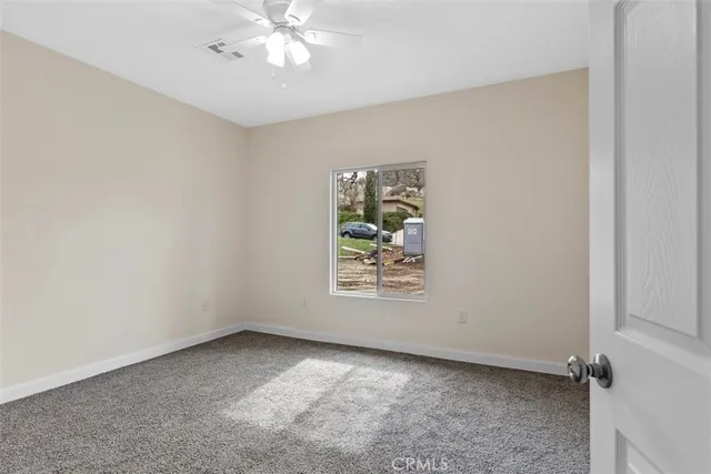an empty room with windows and chandelier fan