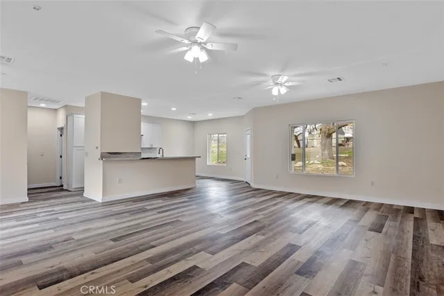 a view of an empty room with a window and wooden floor
