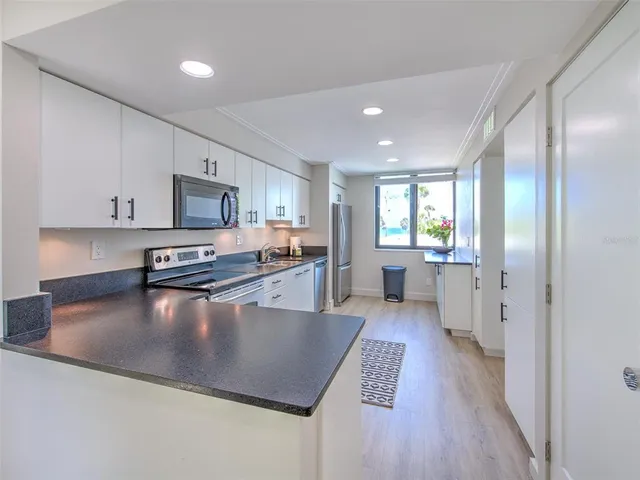 a kitchen with granite countertop a sink cabinets stainless steel appliances and wooden floor