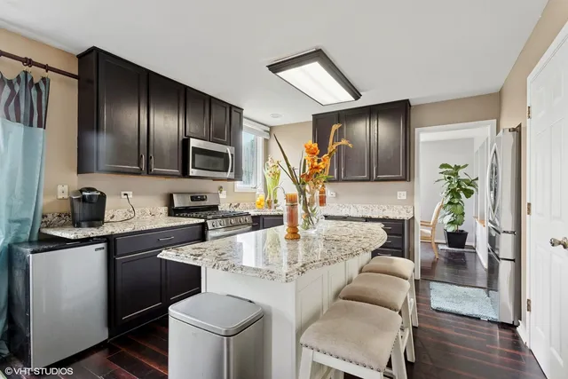 a kitchen with kitchen island granite countertop a sink stove and refrigerator