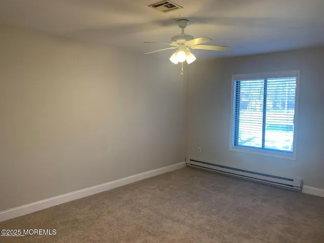 an empty room with a chandelier fan and windows