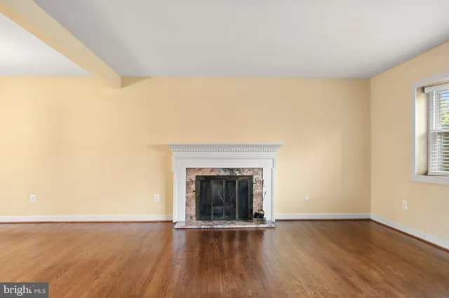 a view of an empty room with wooden floor and a fireplace