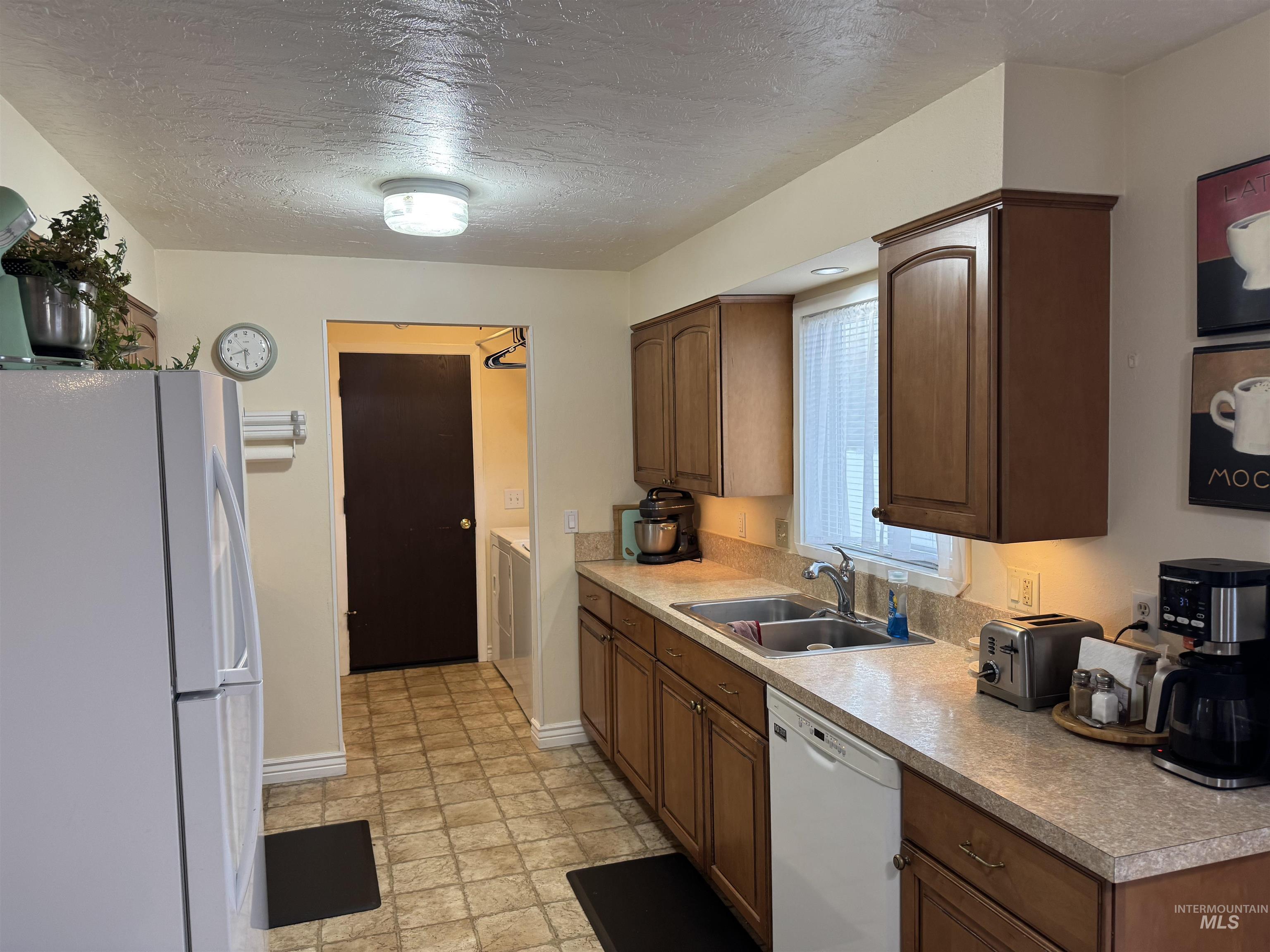 1145 Utah Street Gooding, ID 83330 - Photo 11 of 50 Kitchen with white appliances, a textured ceiling, light countertops, and wood finish cabinets