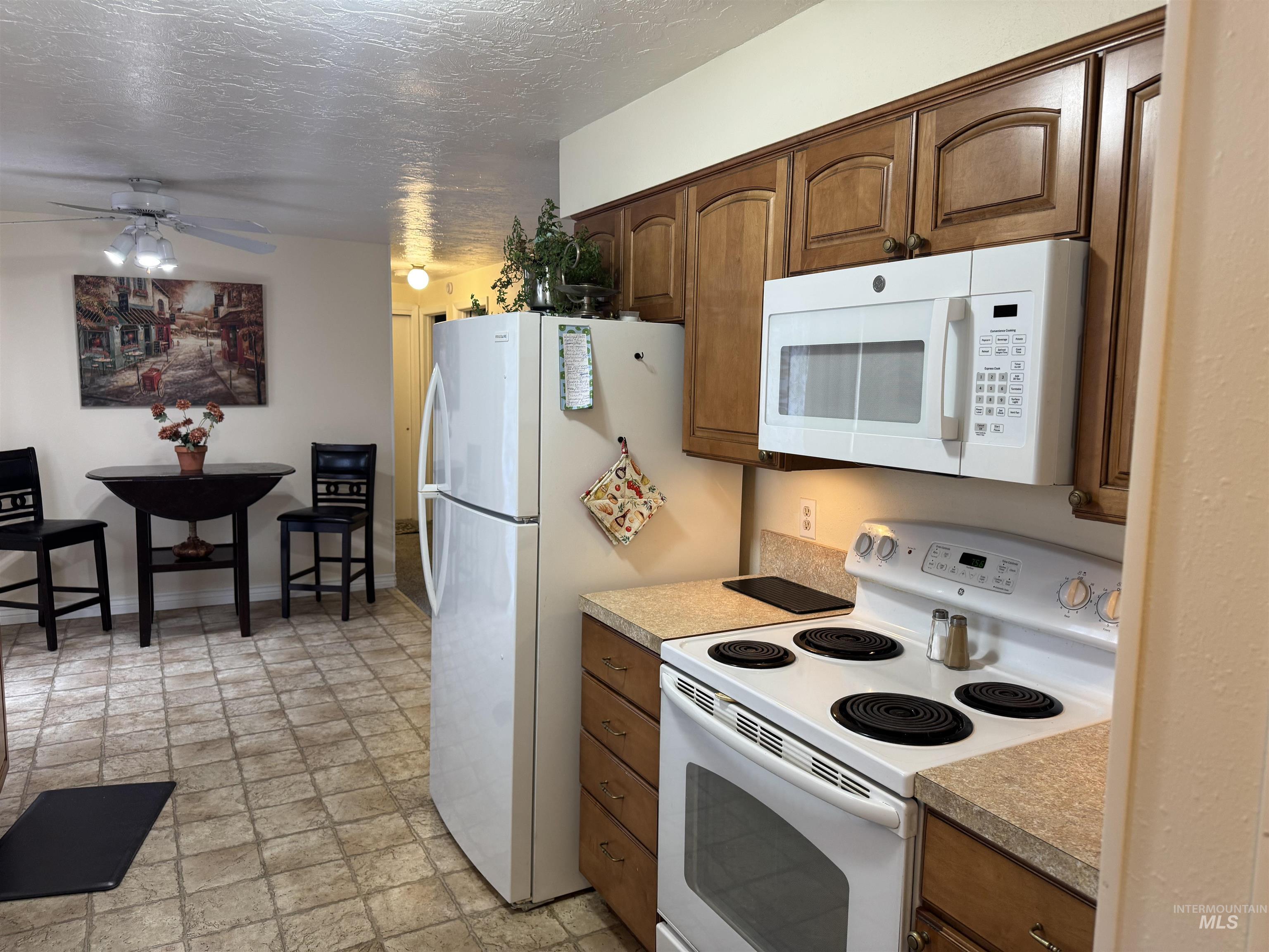 1145 Utah Street Gooding, ID 83330 - Photo 12 of 50 Kitchen featuring white appliances, stone finish flooring, ceiling fan, light countertops, and a textured ceiling
