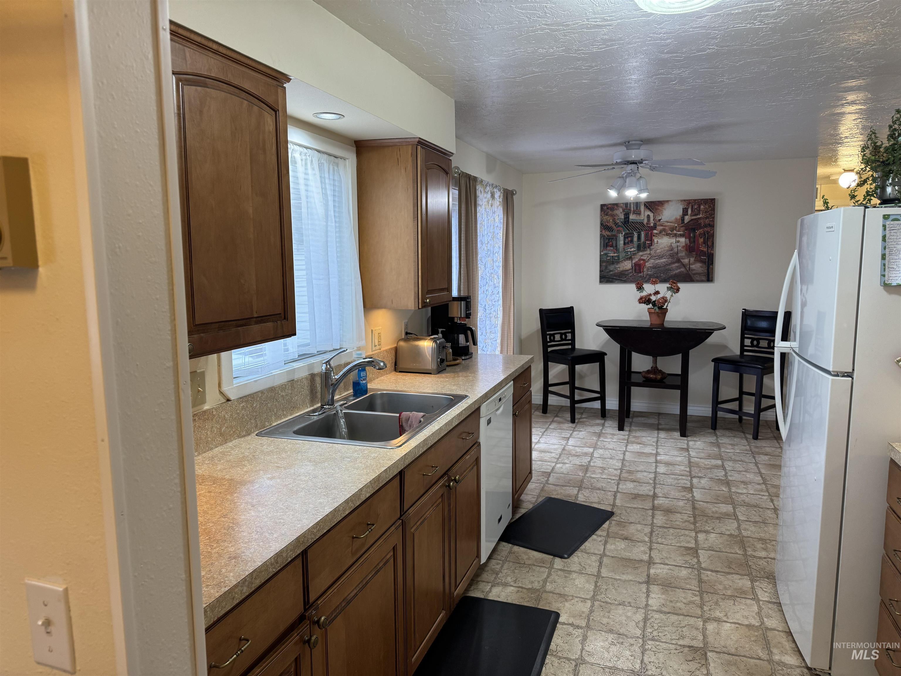 1145 Utah Street Gooding, ID 83330 - Photo 13 of 50 Kitchen with white appliances, light countertops, a ceiling fan, wood finish cabinetry, and a textured ceiling