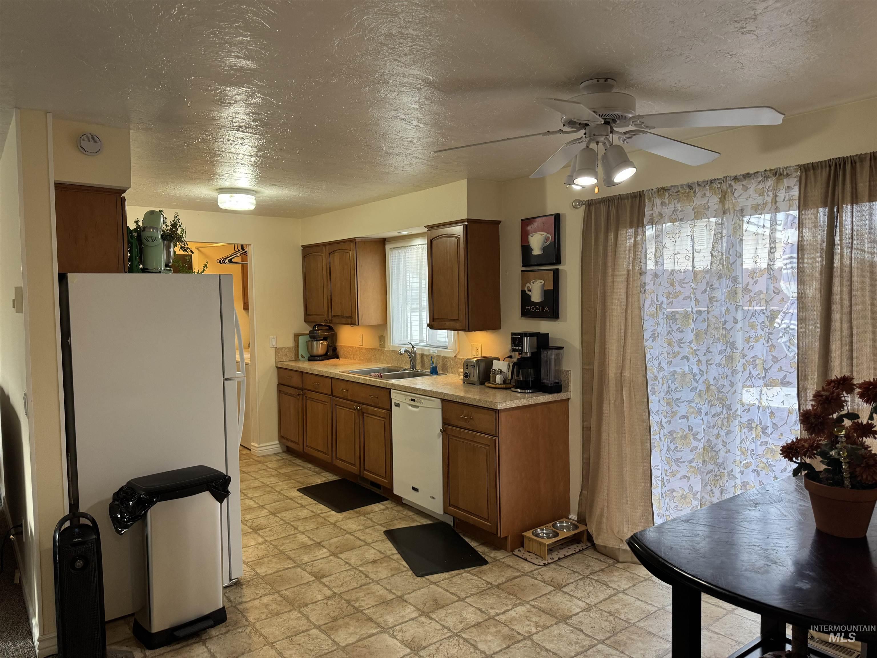 1145 Utah Street Gooding, ID 83330 - Photo 16 of 50 Kitchen featuring a textured ceiling, light countertops, white appliances, wood finish cabinetry, and a ceiling fan