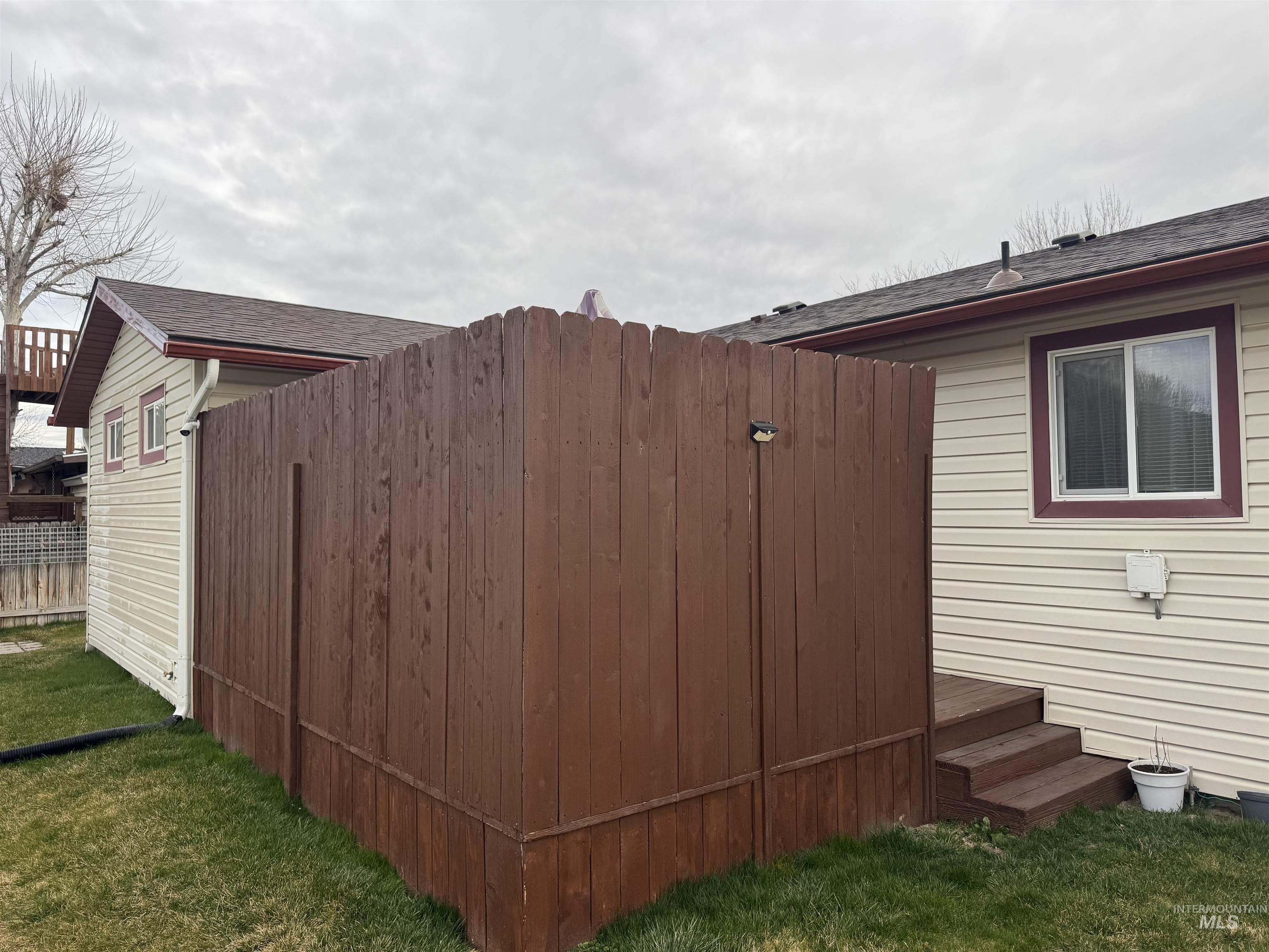 1145 Utah Street Gooding, ID 83330 - Photo 43 of 50 View of side of property featuring roof with shingles, a deck, a lawn, and a gate