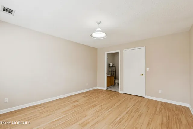 a view of an empty room with wooden floor and fan