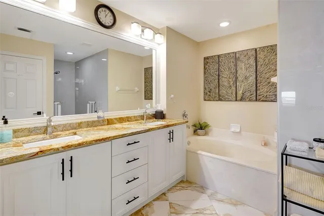 a bathroom with a granite countertop sink mirror and bathtub