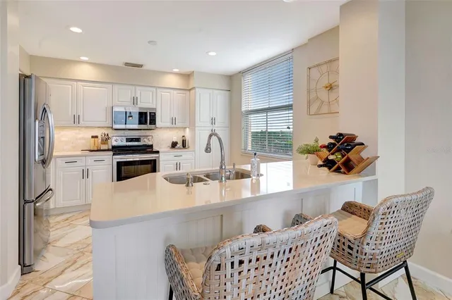 a kitchen with stainless steel appliances kitchen island granite countertop a refrigerator a stove a sink dishwasher and a dining table with wooden floor