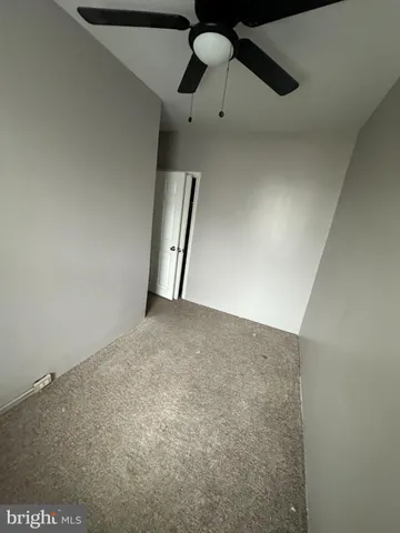 an empty room with staircase and fan