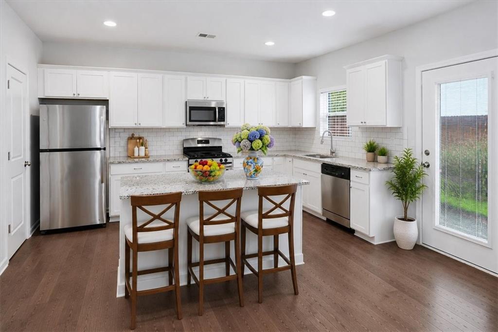 585 Summit Point Canton, GA 30114 - Photo 11 of 30 a kitchen with stainless steel appliances a dining table chairs refrigerator and microwave