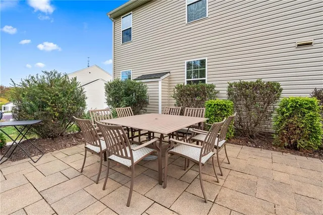 a patio with table and chairs and potted plants