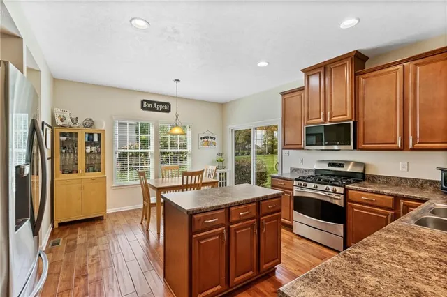 a kitchen with stainless steel appliances granite countertop a stove top oven a sink dishwasher a refrigerator and cabinets with wooden floor