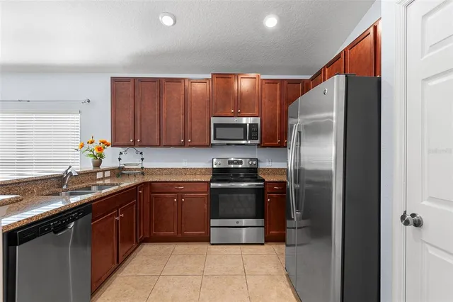 a kitchen with stainless steel appliances granite countertop a sink a refrigerator and a granite counter tops
